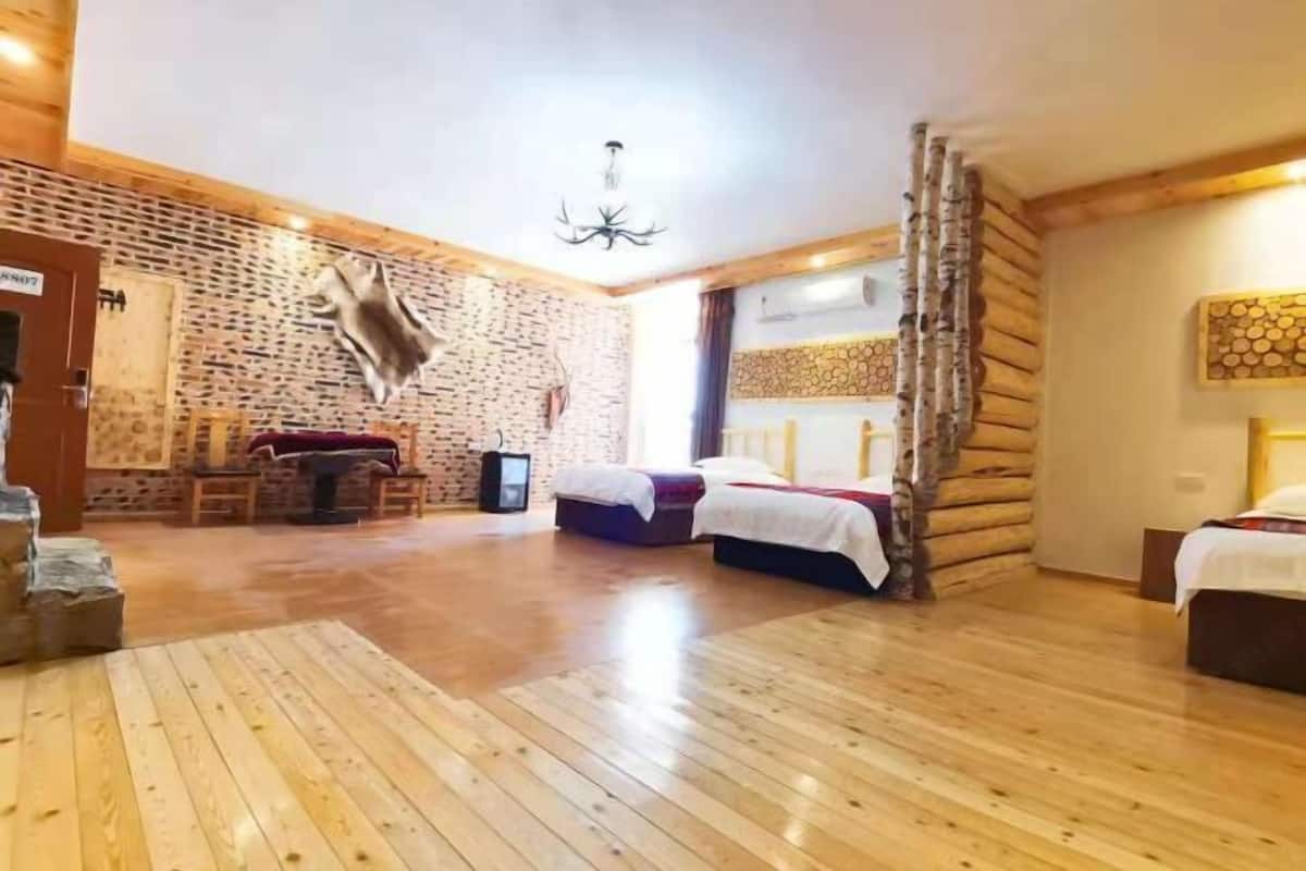A log cabin-style room with two beds, a fireplace, and a stone wall.