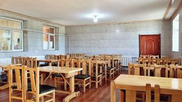 A room with multiple wooden tables and chairs arranged for dining.