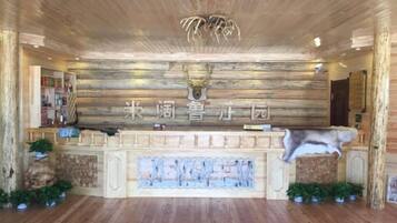 Un área de recepción con un muro de madera, una cabeza de ciervo y un letrero en idioma extranjero.