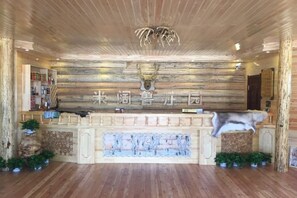 A reception area with a wooden wall, a deer head, and a sign in a foreign language. - Mikuolu Manor (Ergun)