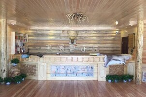 Un área de recepción con un muro de madera, una cabeza de ciervo y un letrero en idioma extranjero.