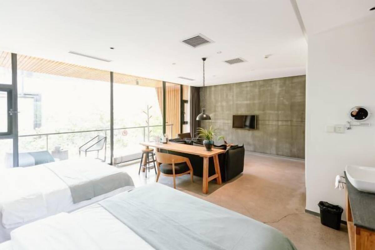 A modern hotel room with two beds, a desk, and a large window.