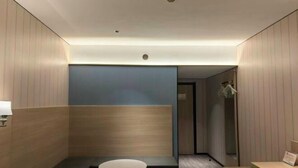 A modern hotel room with a seating area, a small table, and a wall-mounted lamp. - Minjia Hotel(Shanghai Qingpu New City Metro Station Store) (Shanghai)