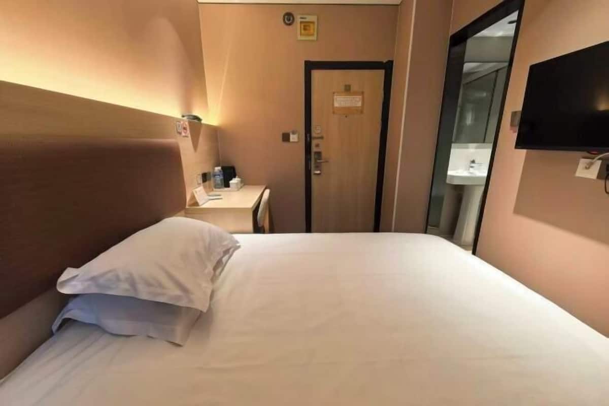Ein Hotelzimmer mit Bett, Schreibtisch, Stuhl, Fernseher und einer Tür.