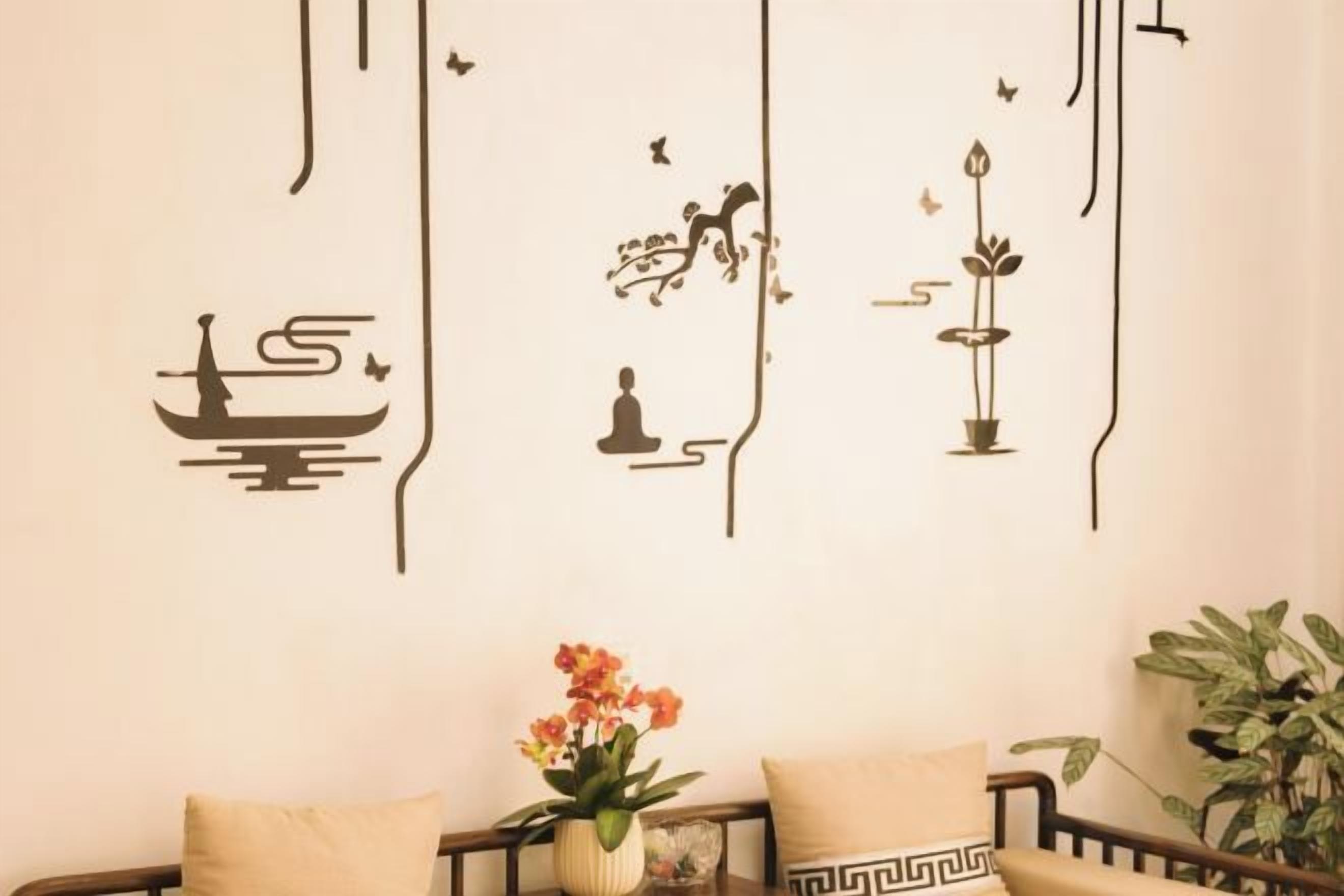 A wall with decorative wall art, a sofa with cushions, and a potted plant.