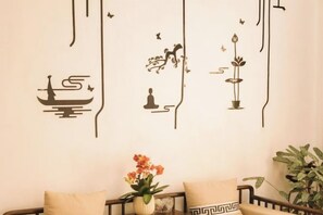 A wall with decorative wall art, a sofa with cushions, and a potted plant. - Residential quarters in Yinqi mountain, Qingdao (Qingdao)