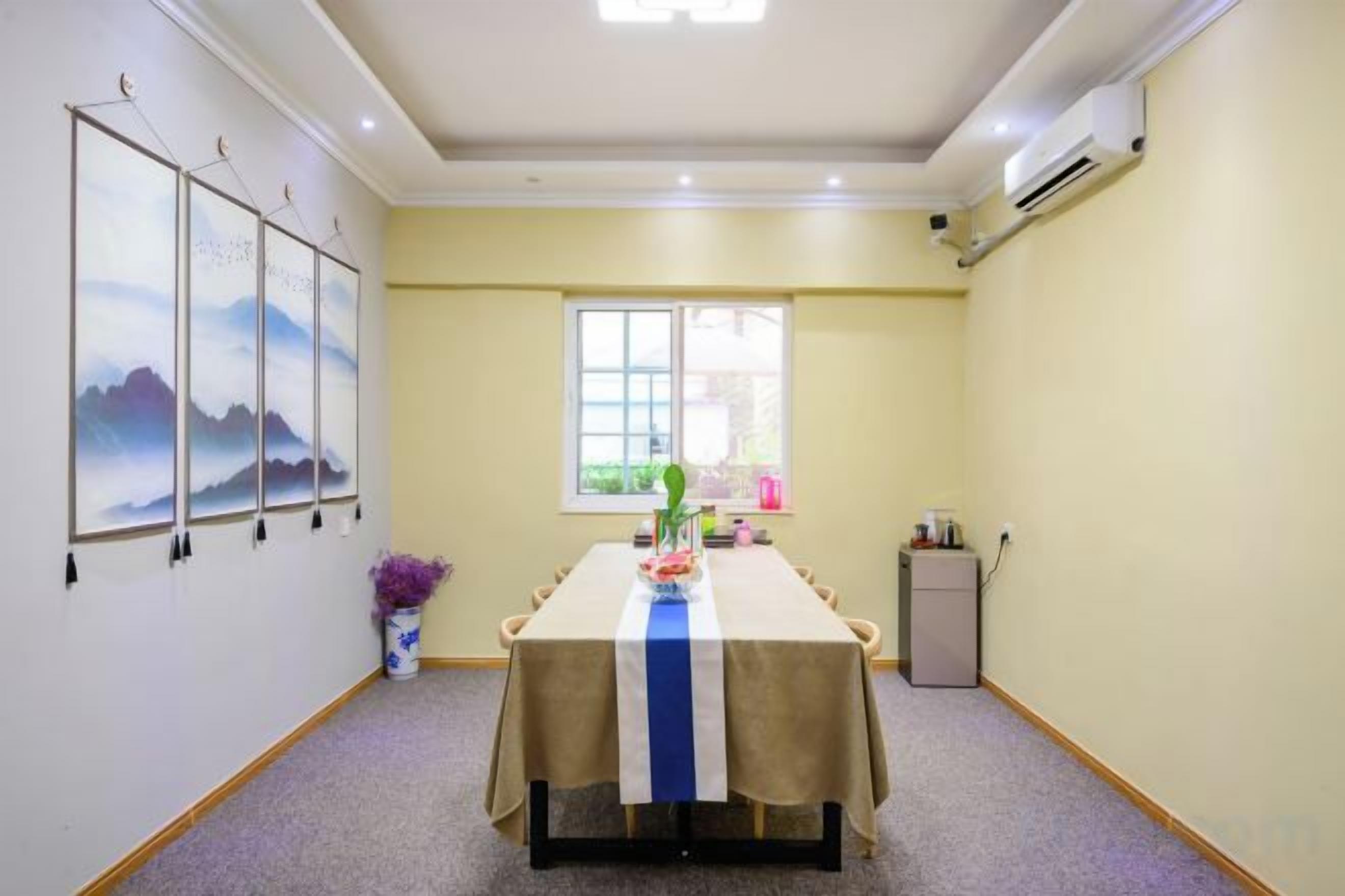 Un salón de conferencias con una larga mesa, un ventanal y un aire acondicionado instalado en la pared.