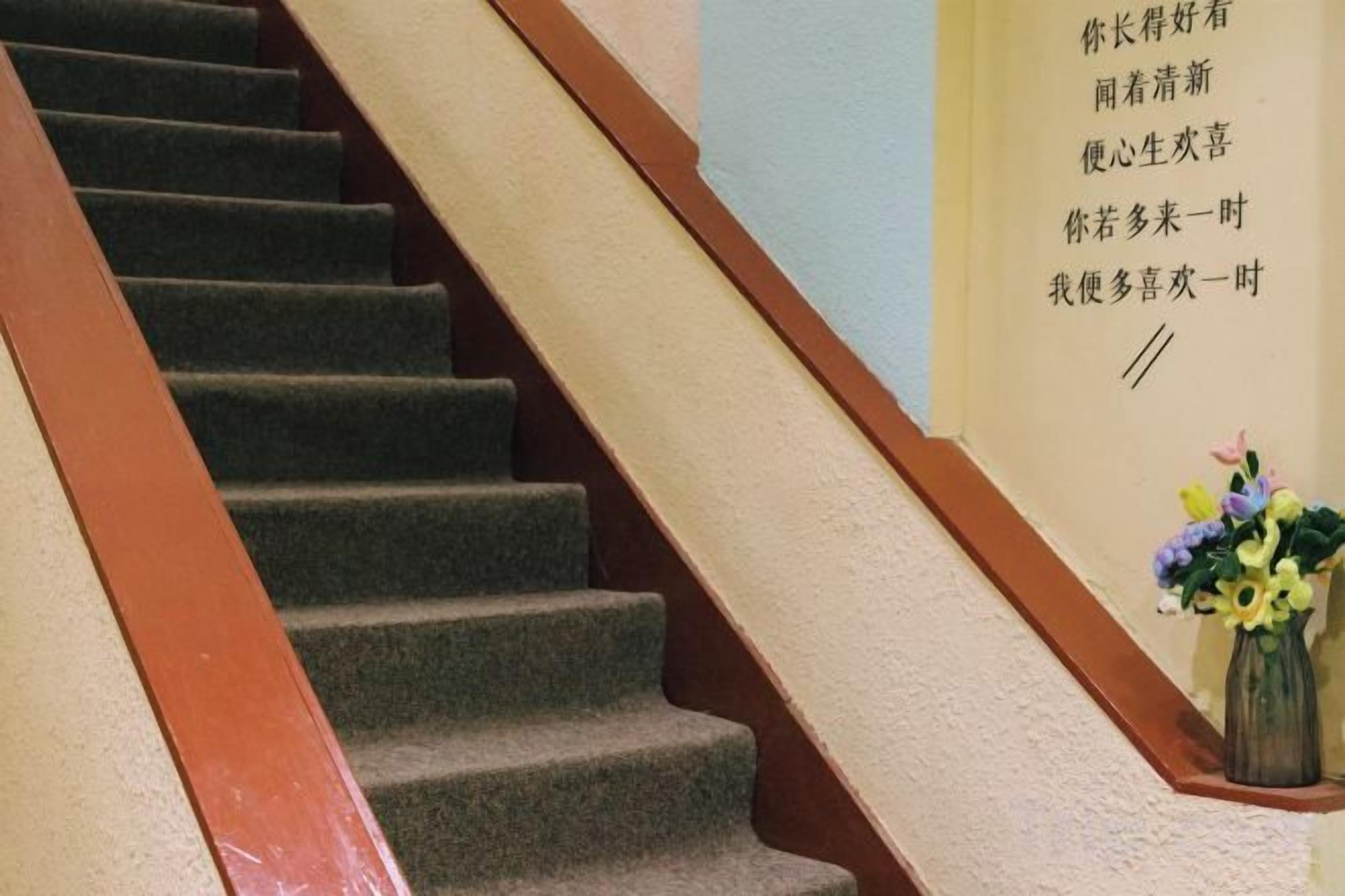 A staircase with a beige wall and a wooden handrail.