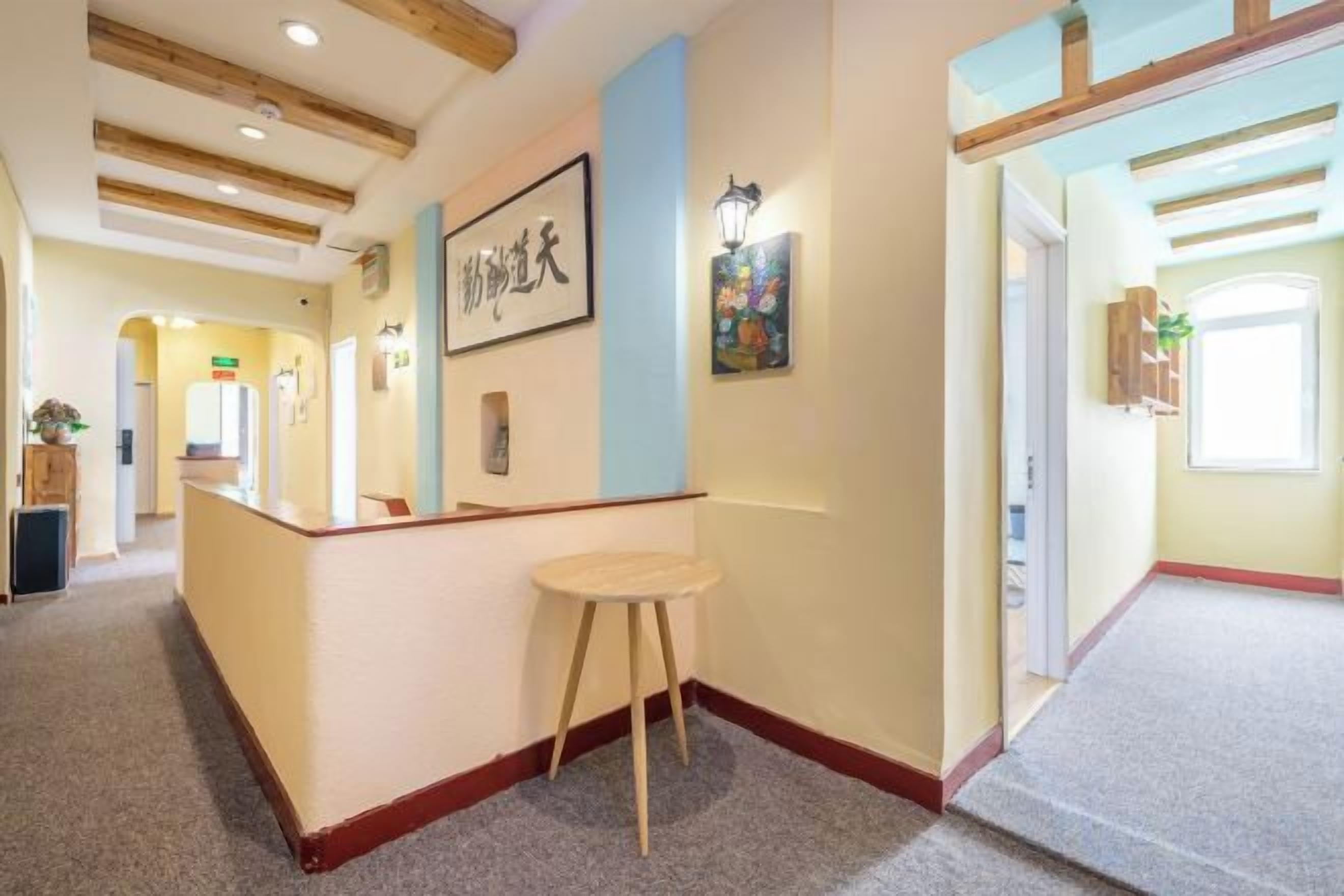 A reception area with a reception desk, a stool, and framed artwork on the wall.