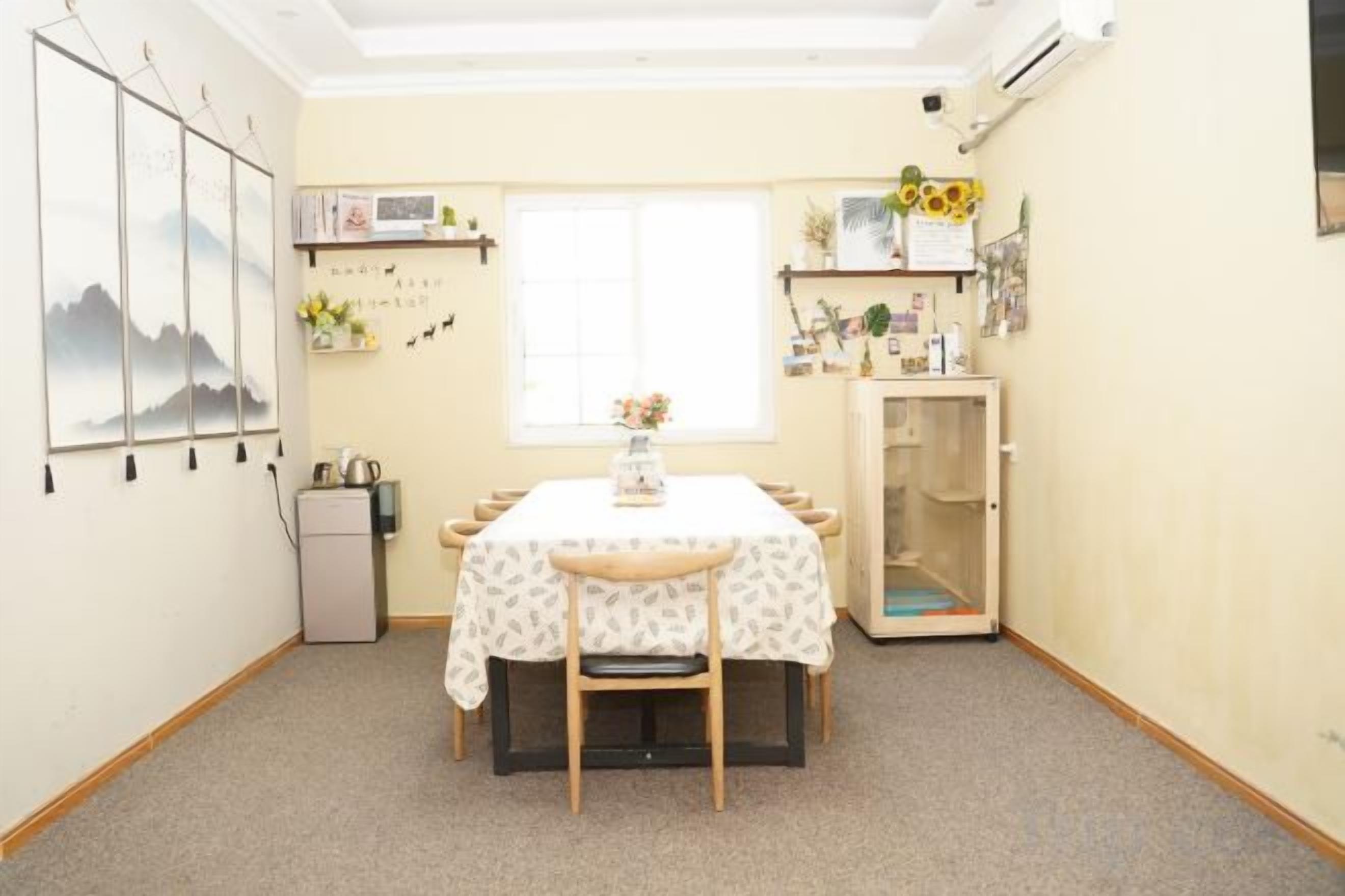 A room with a dining table, chairs, a small cabinet, a radiator, a window, and wall decorations.