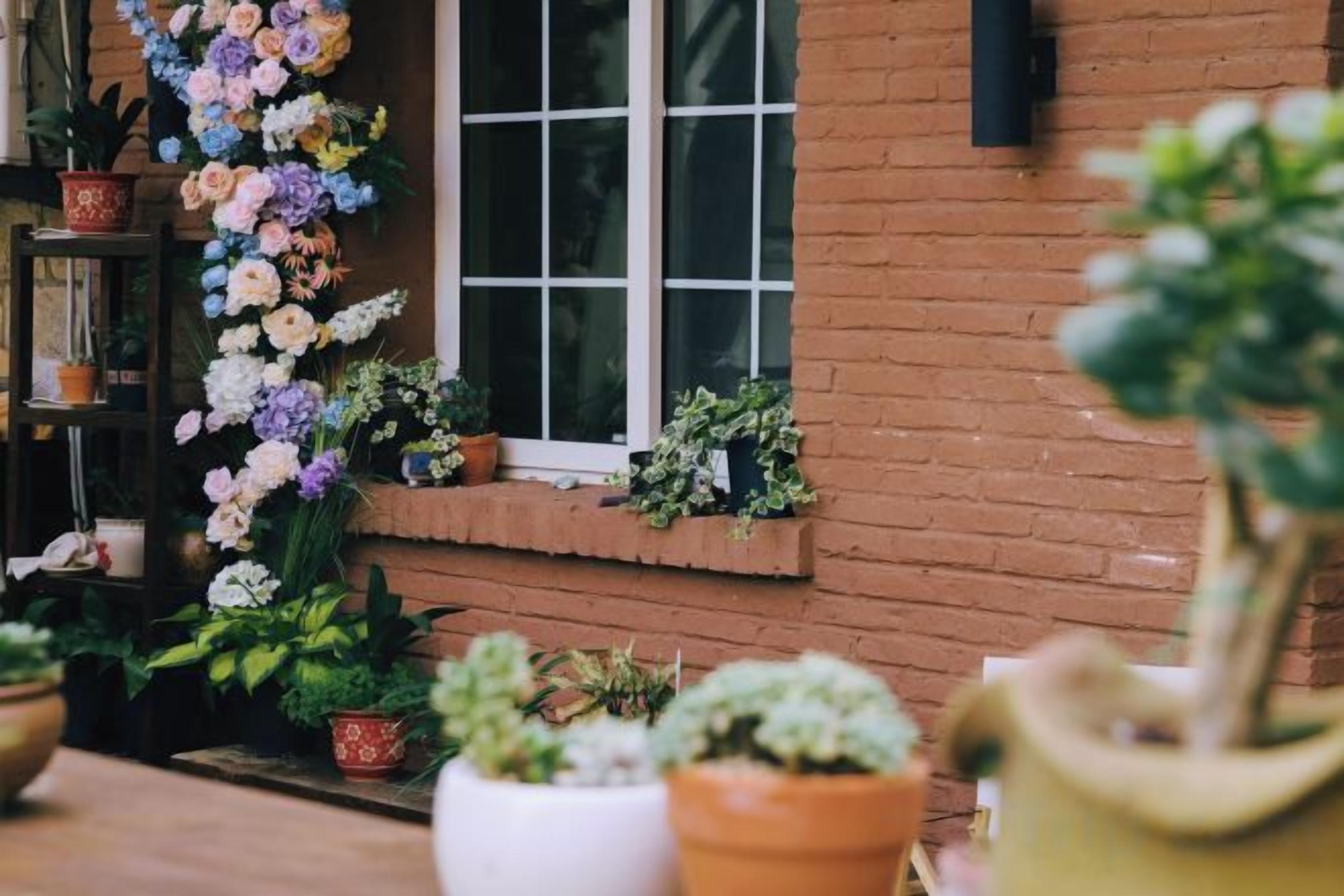 A brick building with a window and a row of potted plants.