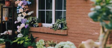 A brick building with a window and a row of potted plants.