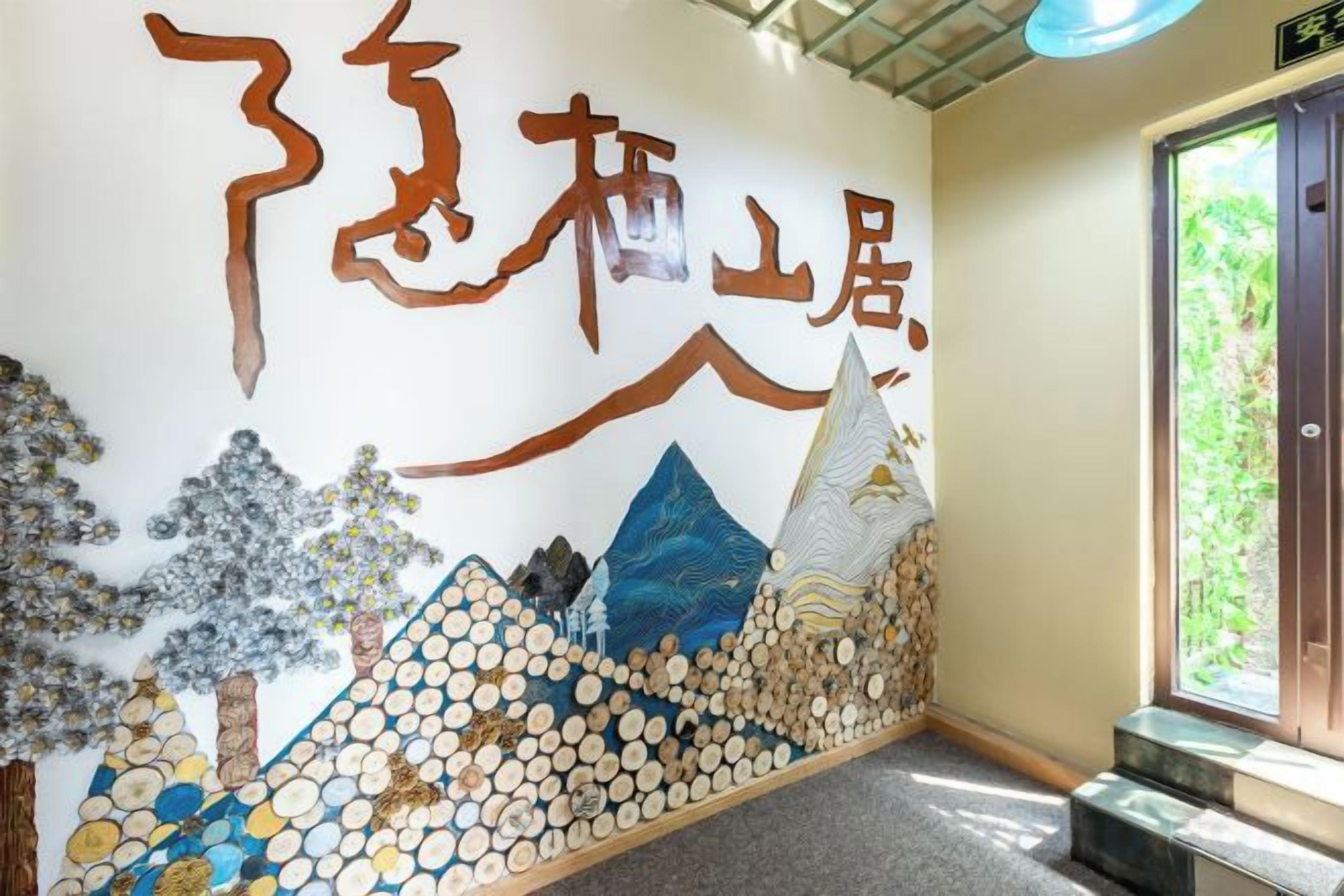 A wall with a mountain and tree illustration, a door, and a window with a view.