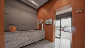 Un espace d’accueil doté d’un comptoir en marbre, de lambris en bois et offrant une vue sur le parking à travers des portes vitrées.