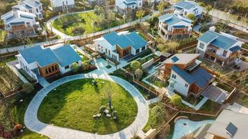 An aerial view of a residential community with modern houses, a central circular driveway, and a swimming pool.