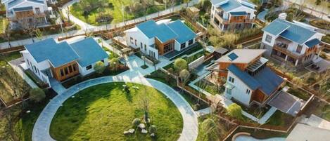 An aerial view of a residential community with modern houses, a central circular driveway, and a swimming pool.