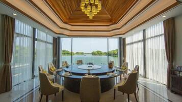 A round table with chairs in a room with large windows and a view of a body of water.