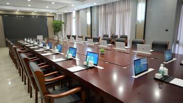 A conference room with a long table, multiple chairs, laptops, and a projector screen.