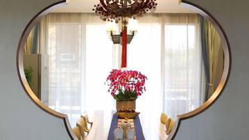 A round mirror reflecting a dining area with a table, chairs, and a vase of flowers.