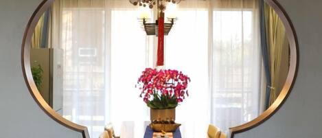 A round mirror reflecting a dining area with a table, chairs, and a vase of flowers.
