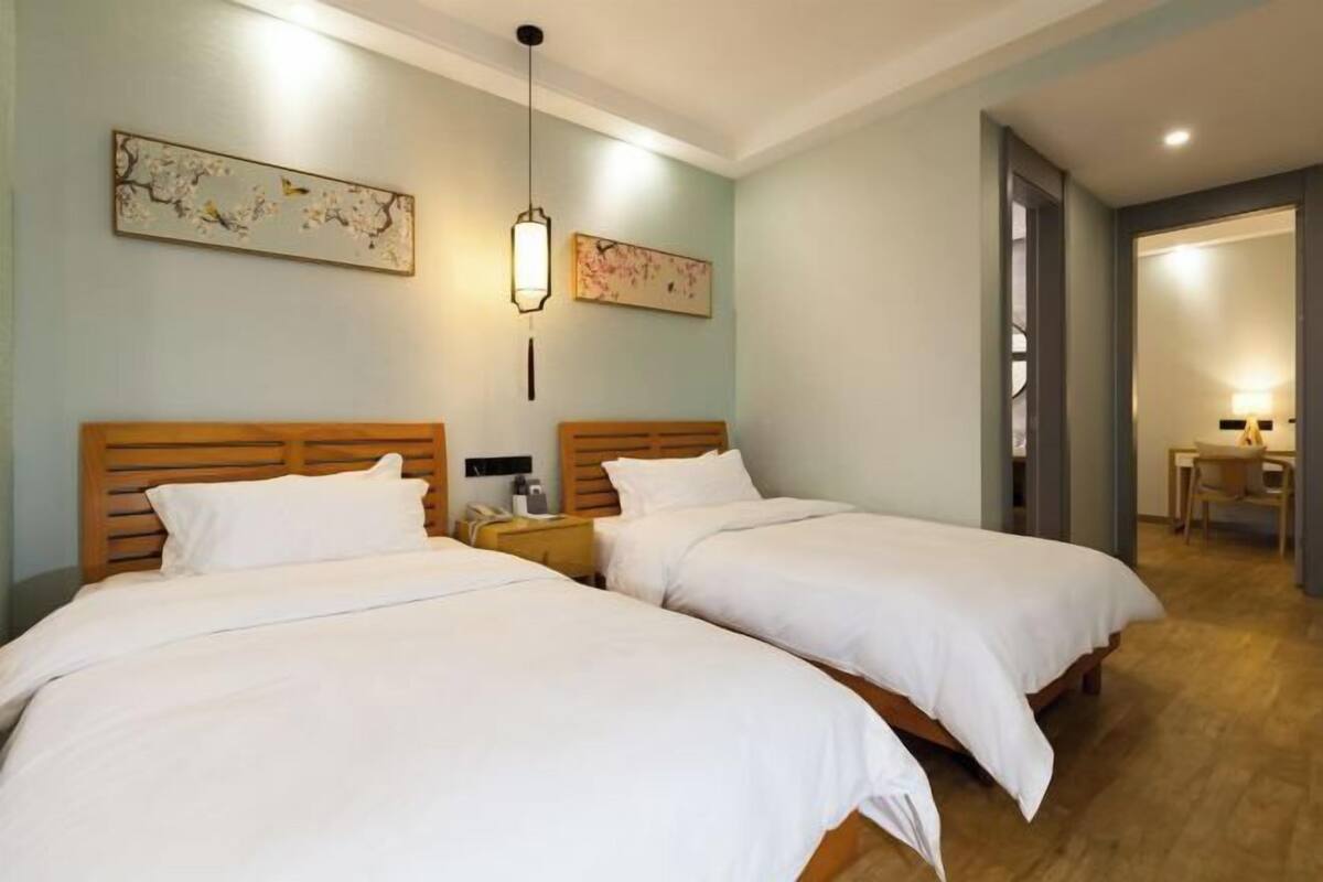 A hotel room with two beds, a wooden headboard, a nightstand, a desk, and a chair.