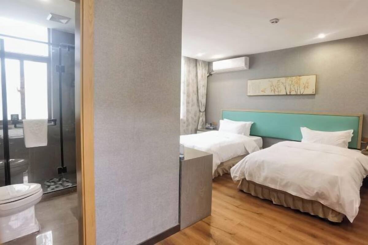 A hotel room with two beds, a shower area, and a toilet.