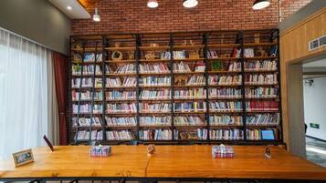 A library with a brick wall, bookshelves, and a wooden table with chairs.