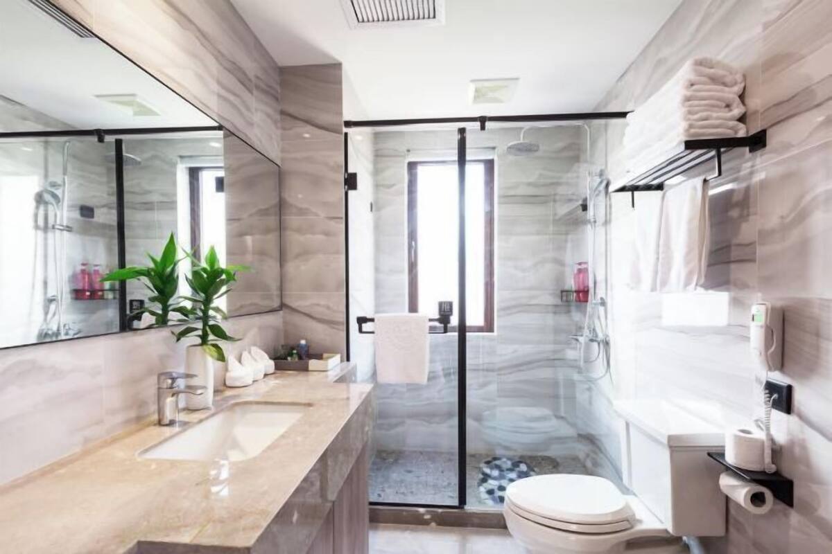 A modern bathroom with a glass shower enclosure, a marble sink, and a toilet.