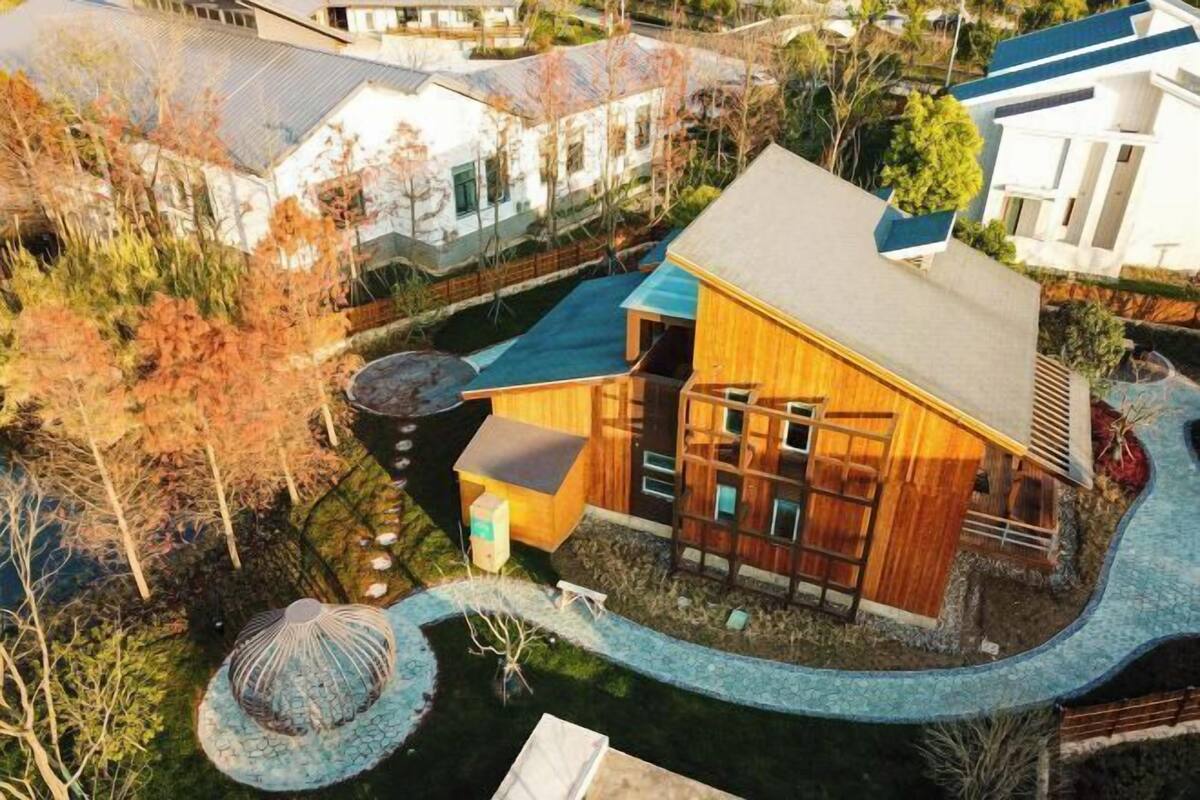 A modern house with a large deck, a small shed, and a circular garden feature.