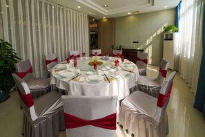 A round dining table with chairs, each with a red sash, set for a meal. - Yingdong Resort (Shanghai)