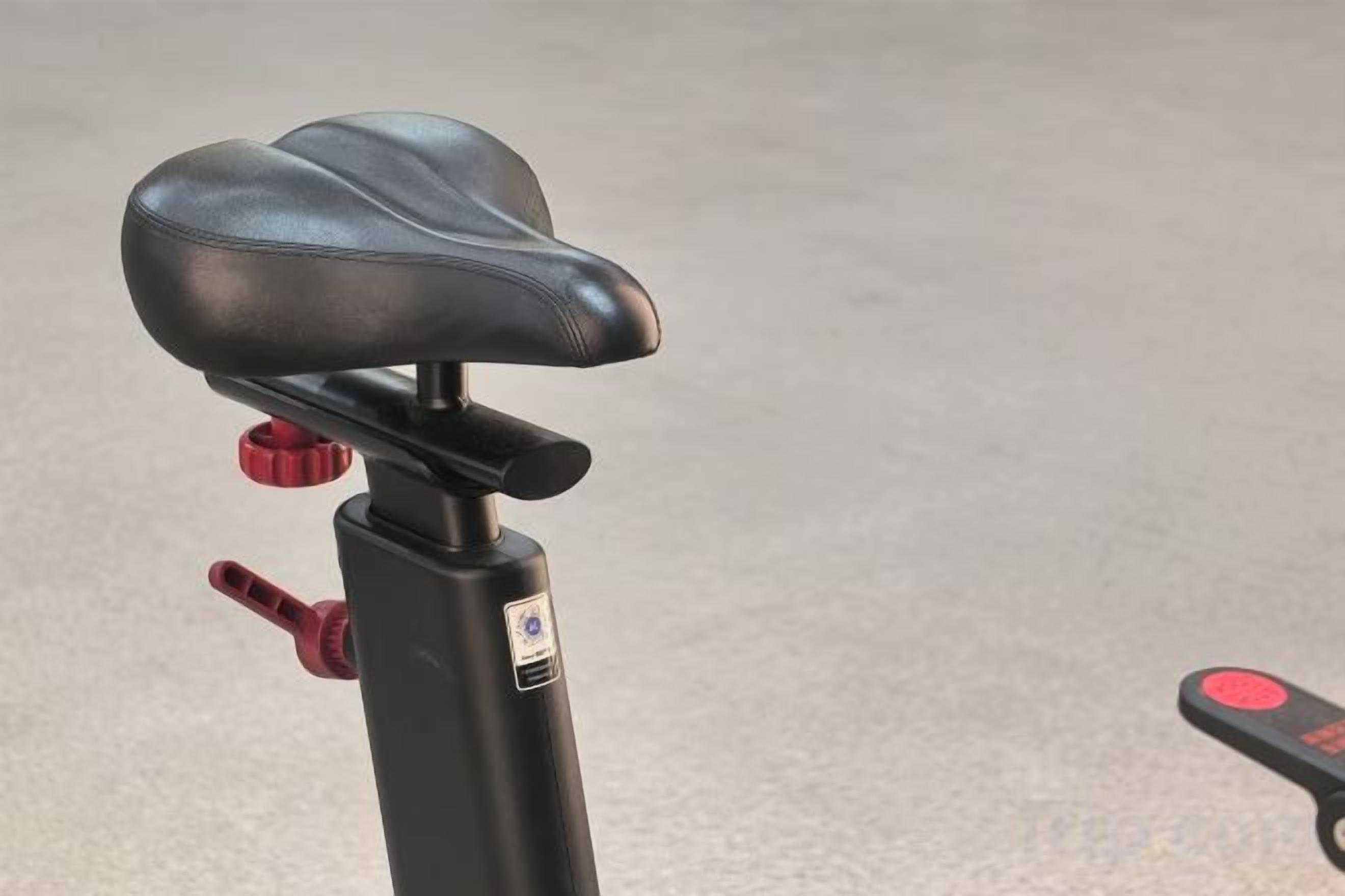 Asiento negro en un patinete con manillar rojo y manillar negro.