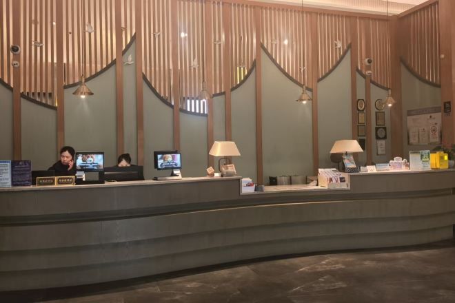A reception desk with two monitors, a telephone, and a lamp.