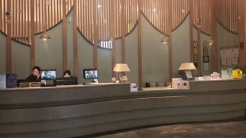 A reception desk with two monitors, a telephone, and a lamp.