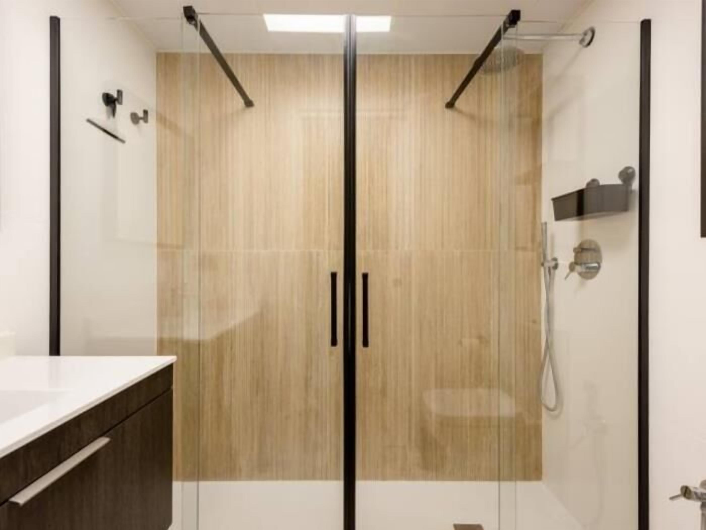 Een moderne badkamer met een houten wastafelmeubel, een douchecabine met glazen wanden en een handdoekrek.