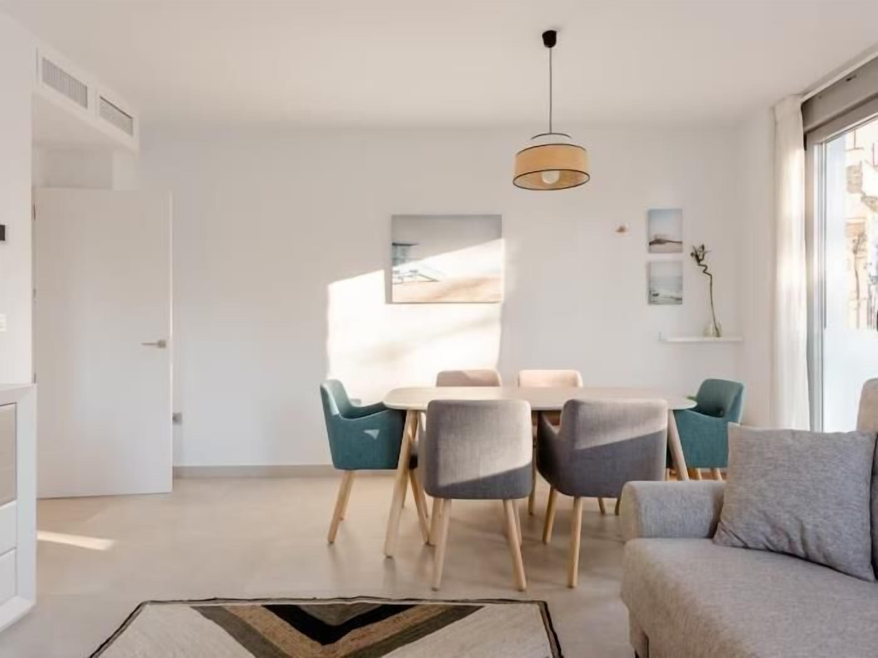 Een moderne woonkamer met een bank, een eettafel met stoelen en een hanglamp.