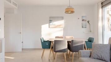 Een moderne woonkamer met een bank, een eettafel met stoelen en een hanglamp.