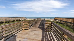 A wooden boardwalk leading to a beach with a clear sky.