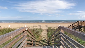 A wooden staircase leading to a beach with a clear sky.