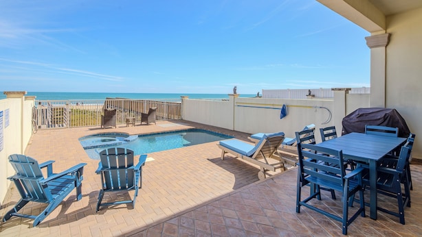 A rooftop pool area with a view of the ocean, a barbecue grill, and outdoor seating.