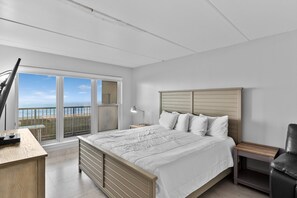 A bedroom with a bed, a desk, a chair, and a nightstand.