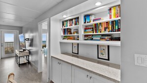 A modern kitchen with white cabinetry, a granite countertop, and a built-in bookshelf filled with books. - Breath-taking Ocean Views, Pool & Hot Tub. 5th Floor Beachfront Views! (South Padre Island)