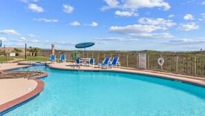 A swimming pool with blue chairs and a lifebuoy, surrounded by a fence and a clear sky. - Breath-taking Ocean Views, Pool & Hot Tub. 5th Floor Beachfront Views! (South Padre Island)