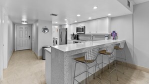 A modern kitchen with a large island, bar stools, stainless steel appliances, and recessed ceiling lights. - Breath-taking Ocean Views, Pool & Hot Tub. 5th Floor Beachfront Views! (South Padre Island)