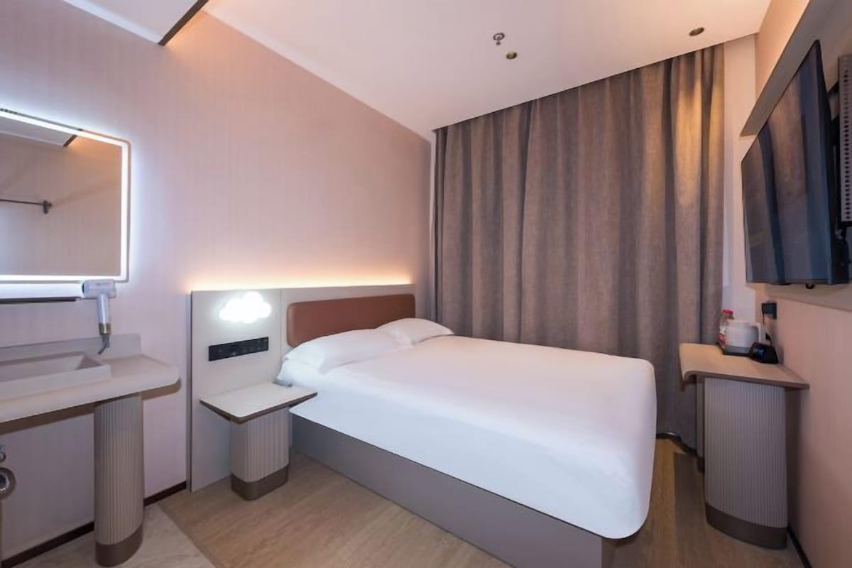 Quarto de hotel com cama, mesa de cabeceira e espelho.