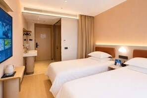 Habitació d'hotel amb dos llits, un vàter, un mirall, una televisió i una tauleta de nit.