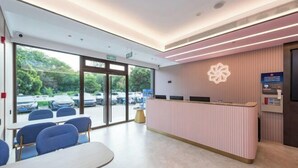 A reception area with a counter, seating, and a view of parked cars outside. - Beijing Luji Hotel Select (Qinghe High-speed Railway Station Branch) (Beijing)