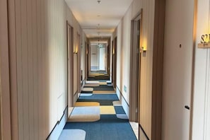 A hotel hallway with a checkered carpet, doors on both sides, and a light fixture on the wall. - Beijing Luji Hotel Select (Qinghe High-speed Railway Station Branch) (Beijing)