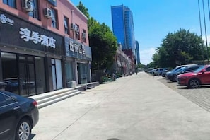 A street with buildings, parked cars, and a clear sky.