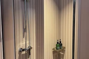 A bathroom with a shower, a mirror, and a shelf with two bottles. - Beijing Luji Hotel Select (Qinghe High-speed Railway Station Branch) (Beijing)