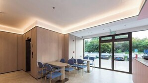 A modern hotel lobby with a reception desk, seating area, and large glass doors leading outside. - Beijing Luji Hotel Select (Qinghe High-speed Railway Station Branch) (Beijing)